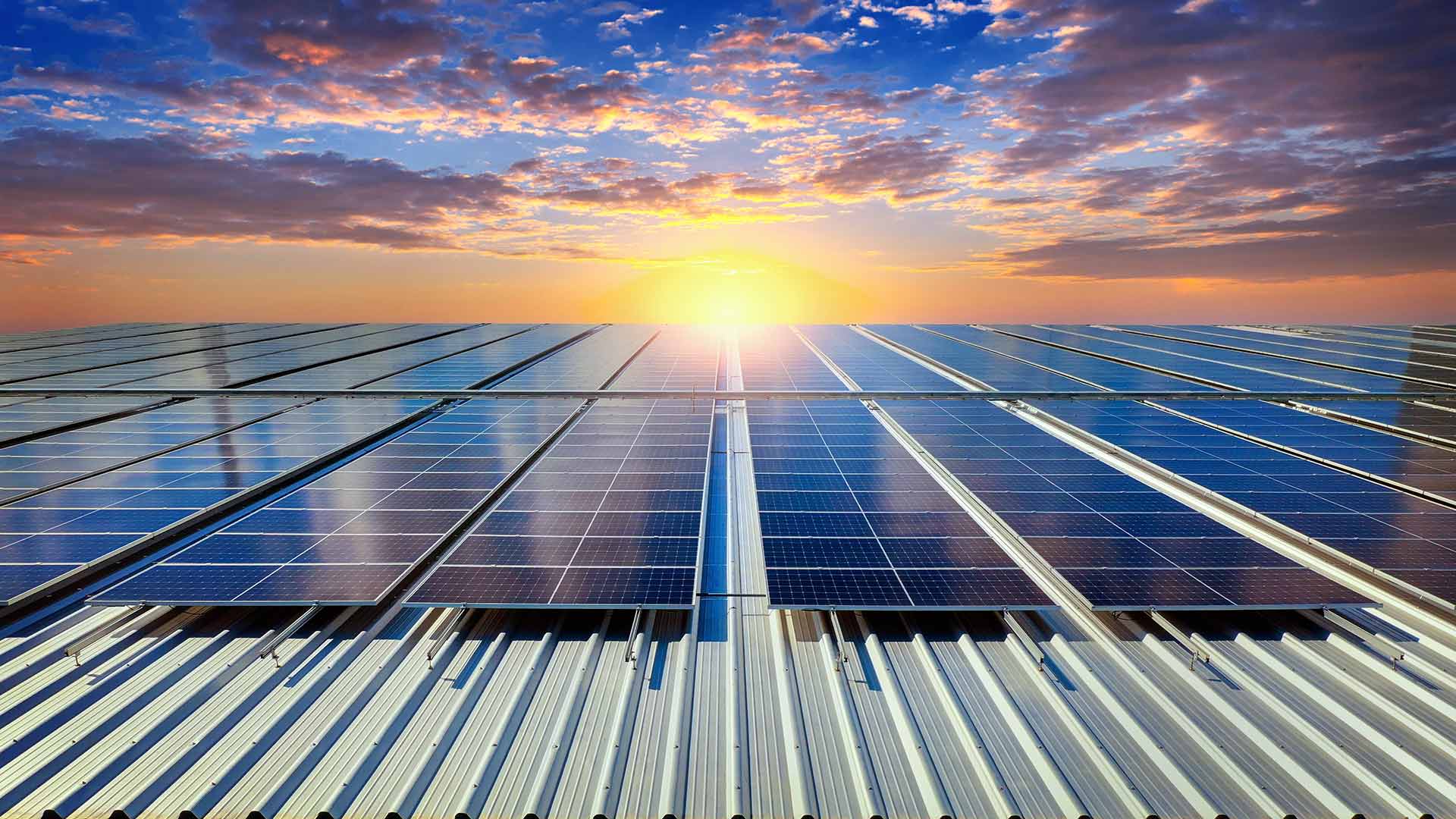 Solarni paneli na krovu industrijskog objekta u zalasku sunca